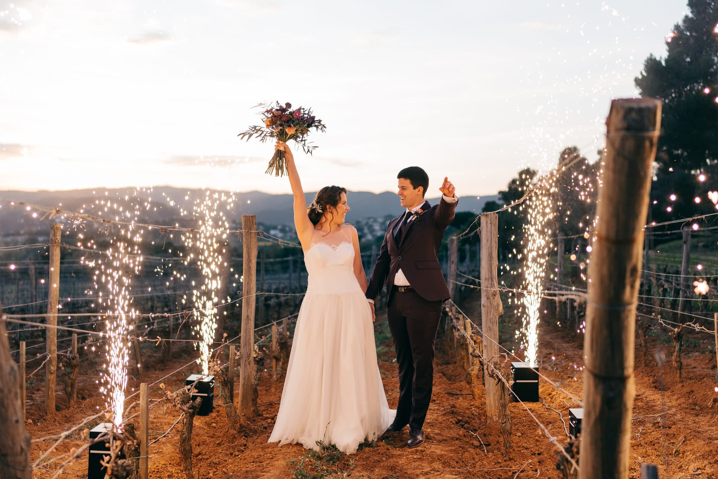 Una pareja de novios celebra entre las viñas con bengalas al atardecer
