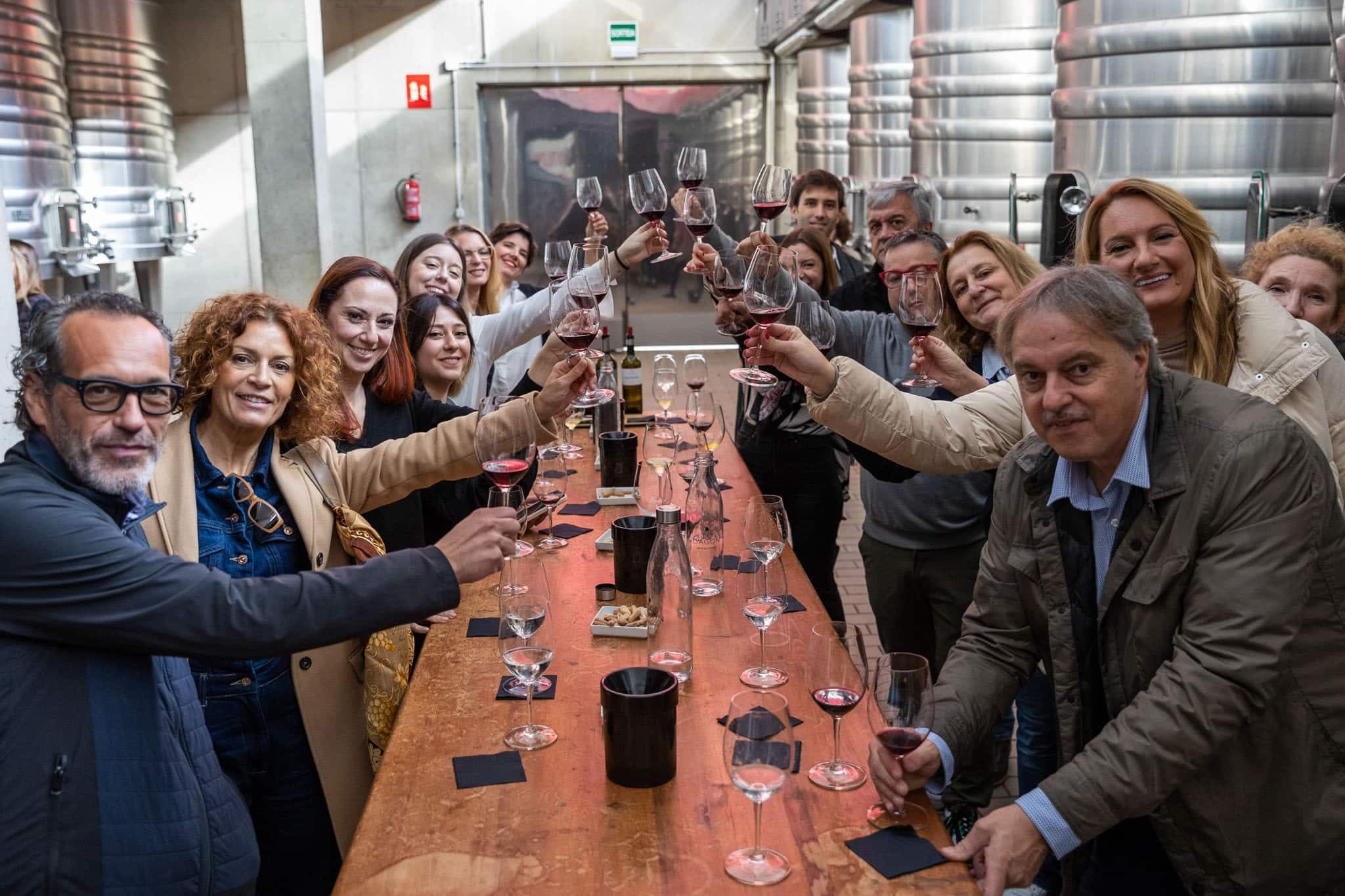 Grupo de empresa brindando en una mesa larga en la bodega